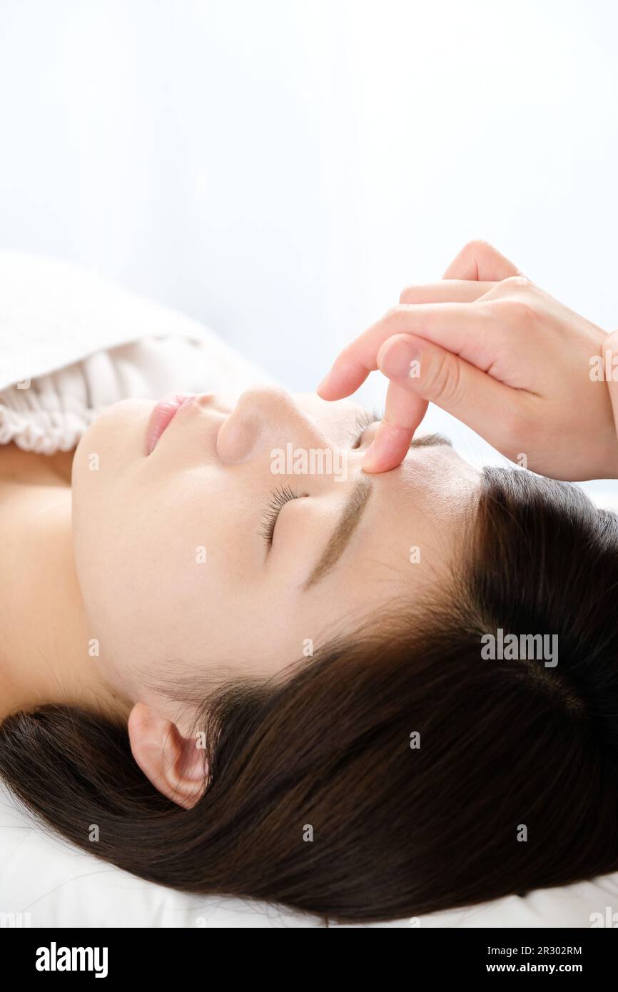 Woman receiving acupressure between the eyes at an acupuncture clinic Stock Photo