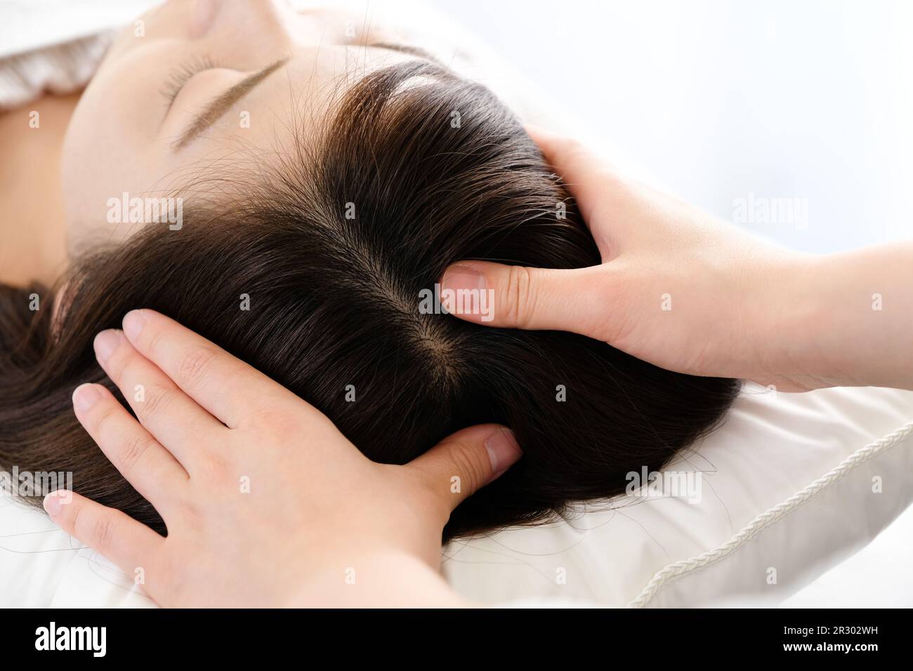 Woman receiving a scalp massage and the practitioner's hand Stock Photo