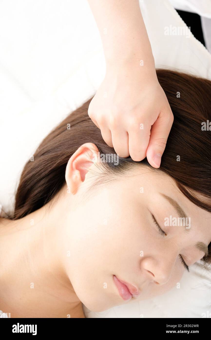 A woman receives pressure on her temples at an acupuncture clinic Stock Photo