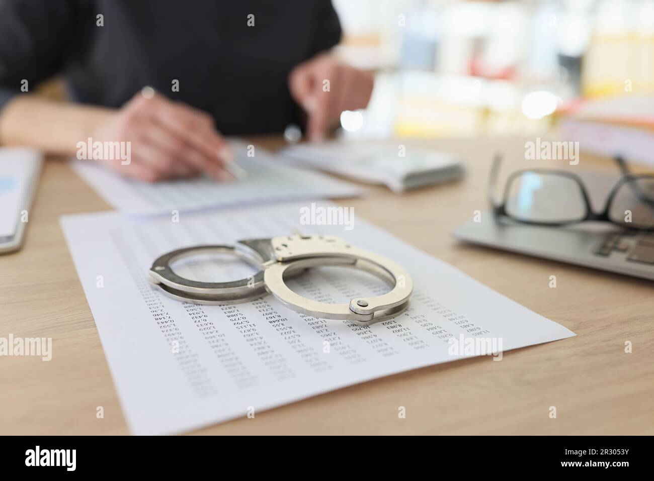 Handcuffs on investigation paper while worker making counts Stock Photo