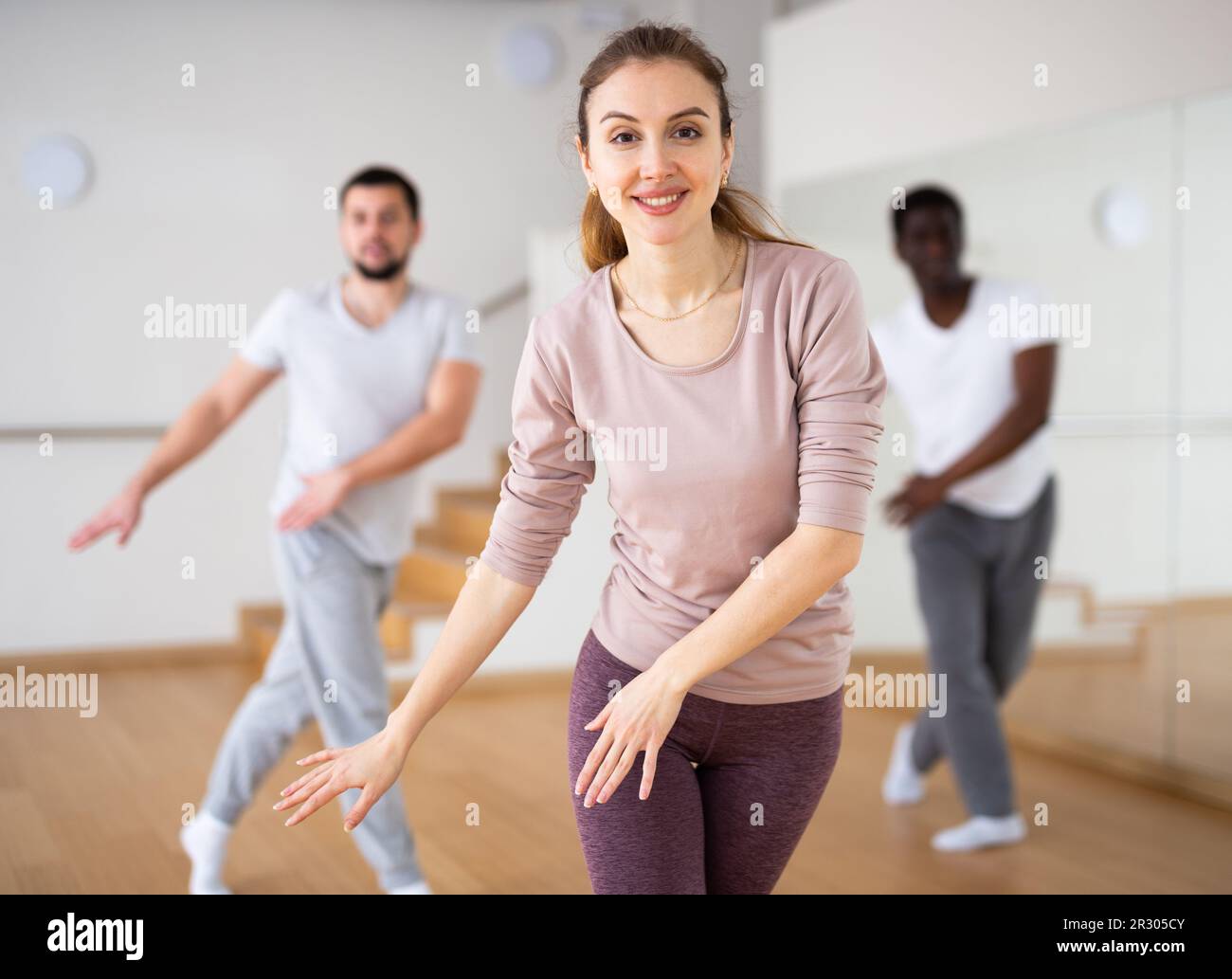 Woman dancing aerobic dance with men in studio Stock Photo