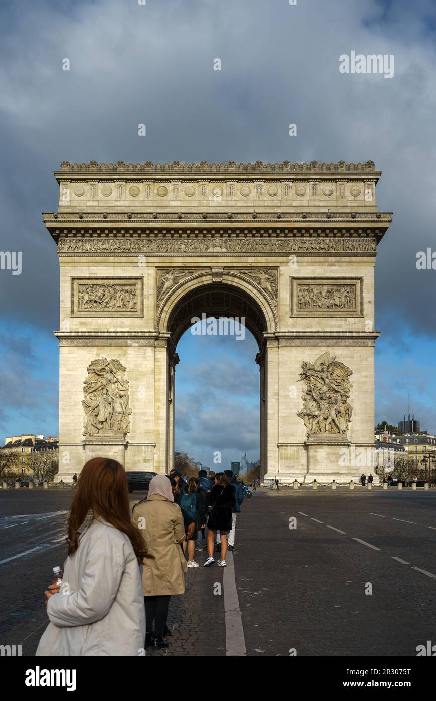 Tourists on Champs-Elysees in front of the Arc de Triomphe in Paris, France. March 25, 2023. Stock Photo