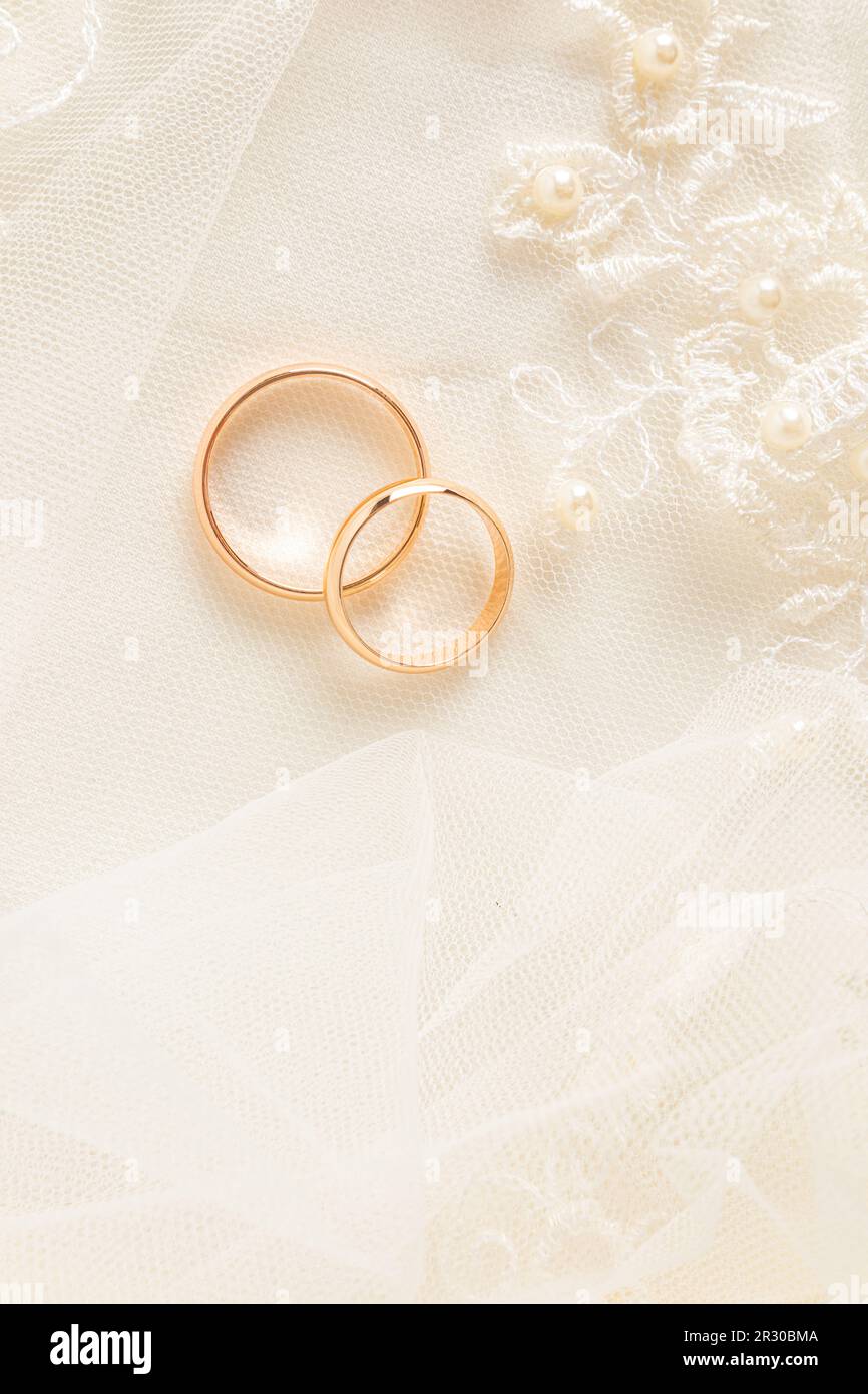 A chic vertical feed for two gold wedding rings on a beige satin