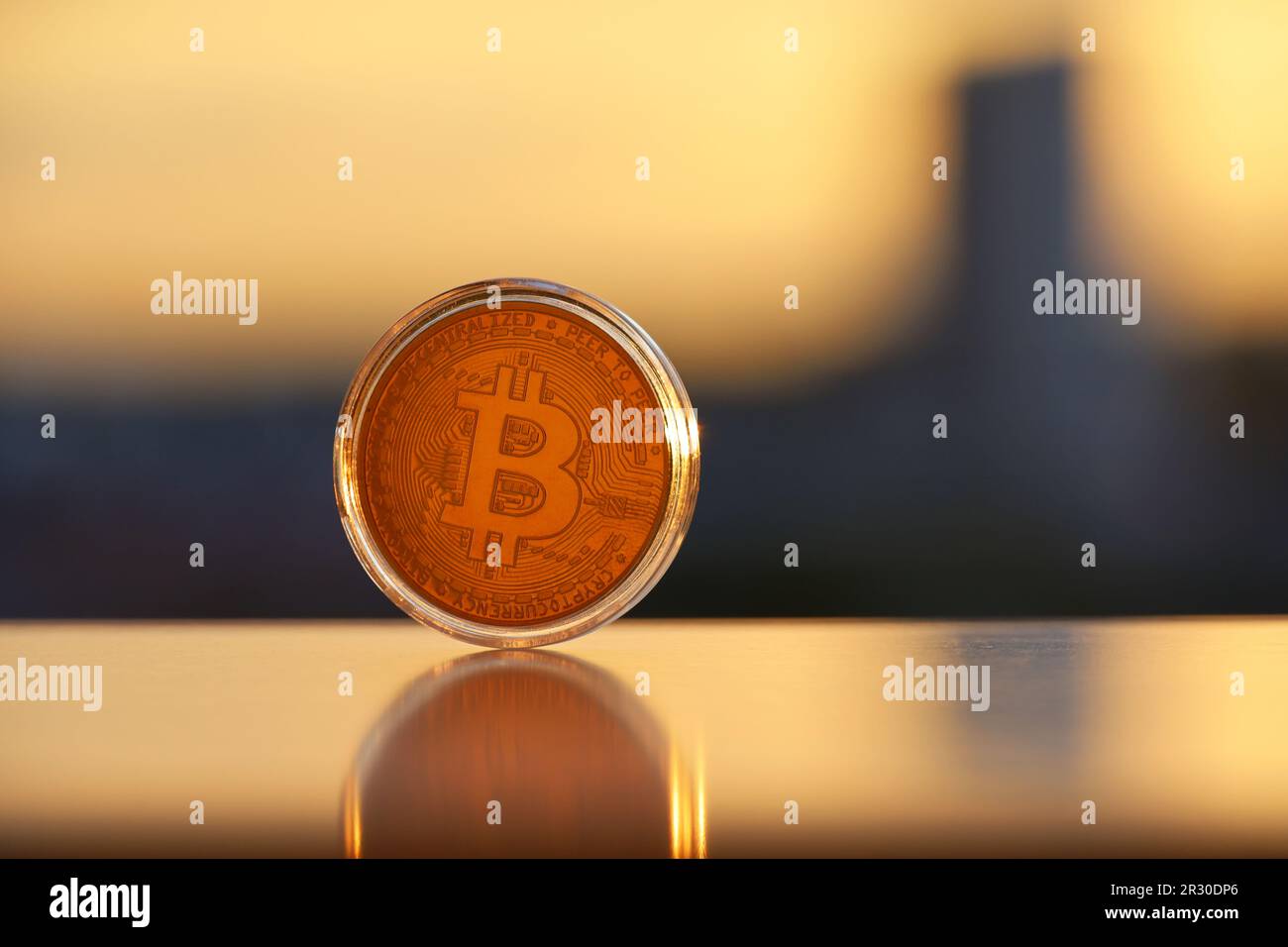 Bitcoin on blurred city background at sunset. Electronic decentralized money, rate of cryptocurrency Stock Photo