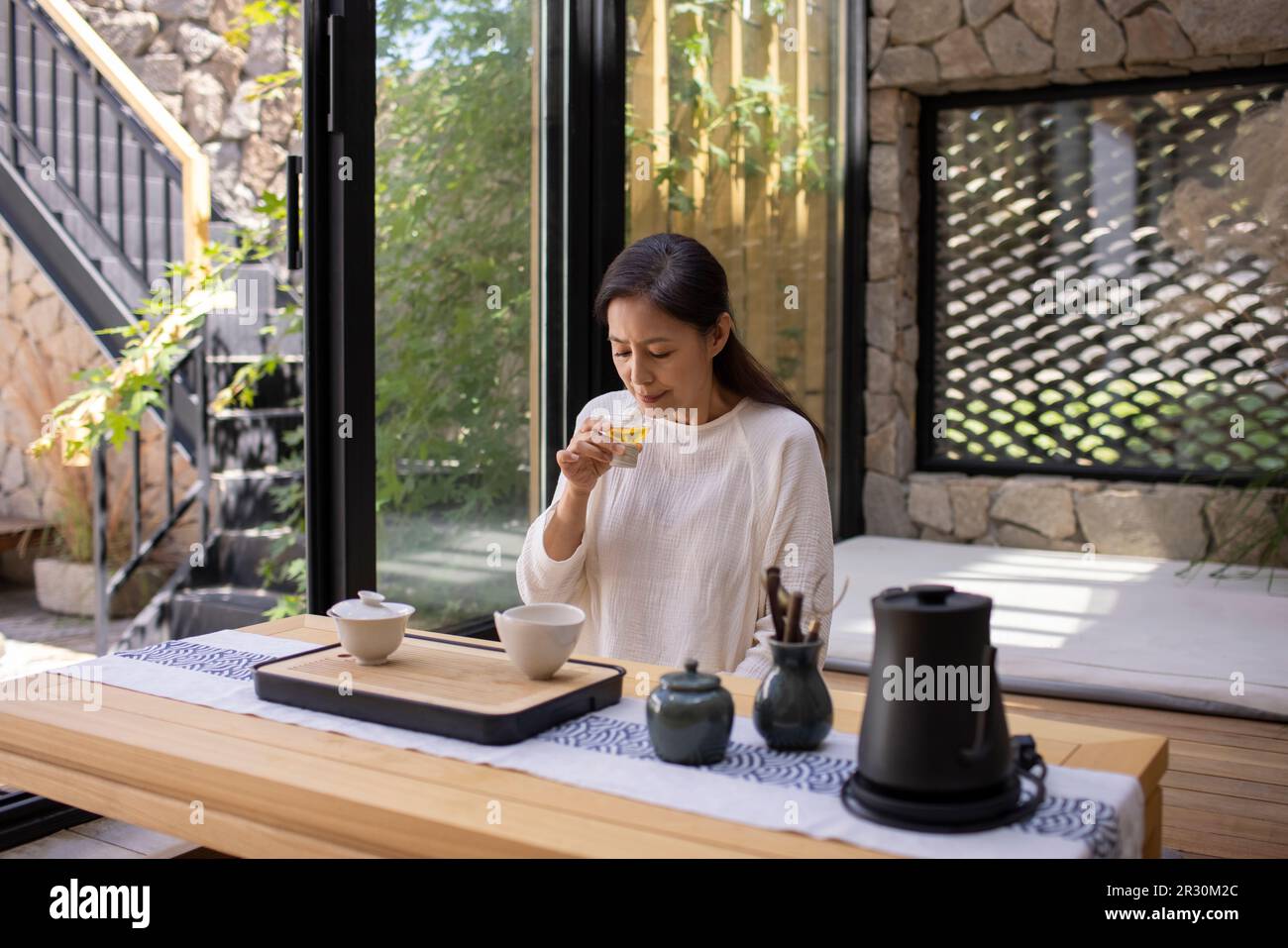 Elegant mature Chinese woman drinking tea in tea room Stock Photo - Alamy