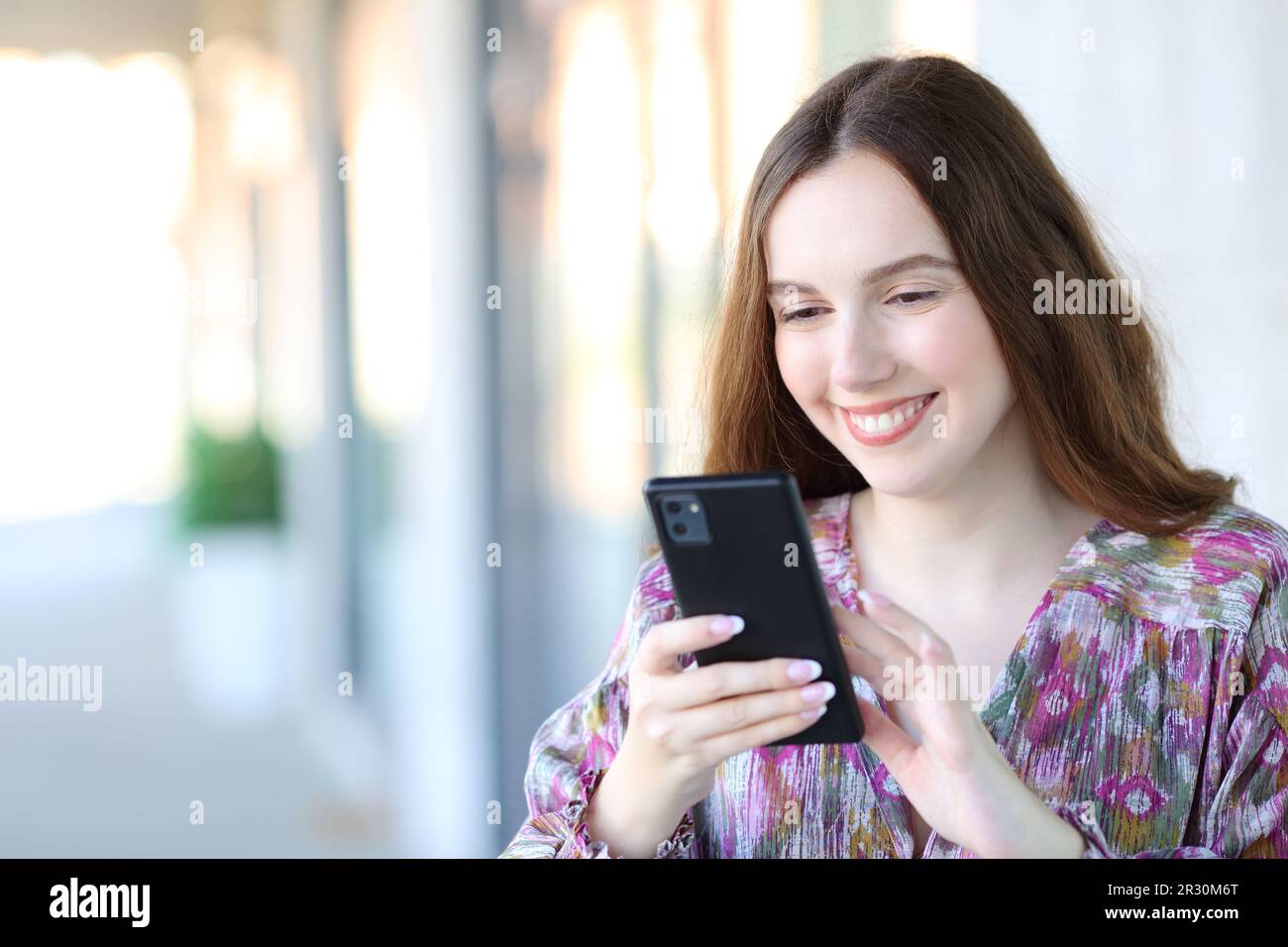 Happy female using smart phone walking in the street Stock Photo