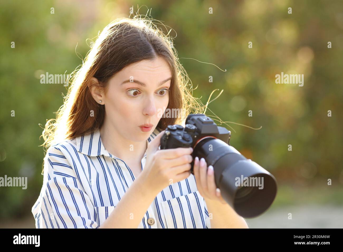 Amazed photographer checking result on mirrorless camera in a park Stock Photo