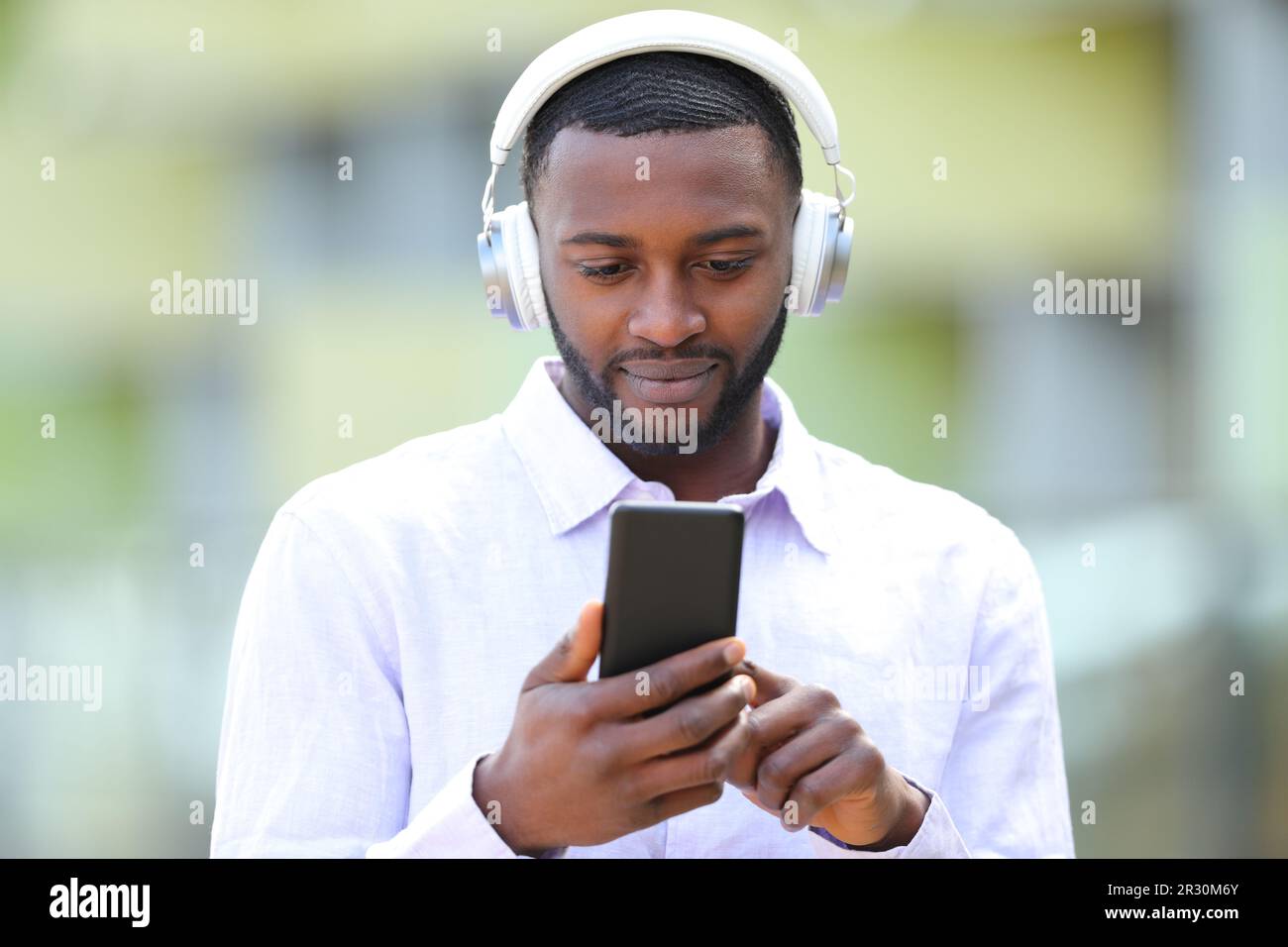 Front view portrait of black man listening to music wearing headphones in the street Stock Photo
