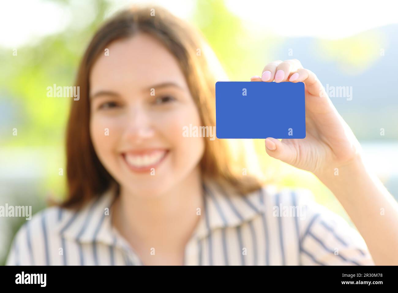 Happy woman showing blank credit card at camera in nature Stock Photo