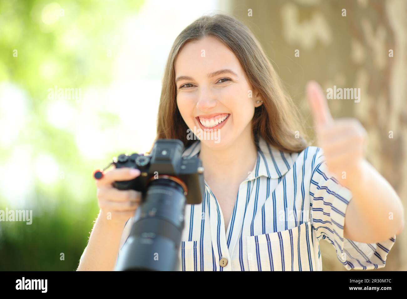 Happy photographer looking at you with thumbs up in nature Stock Photo