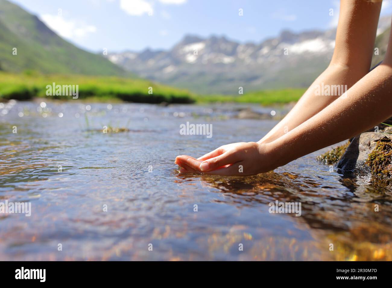 Close up of a woman hands catching water from mountain river Stock Photo