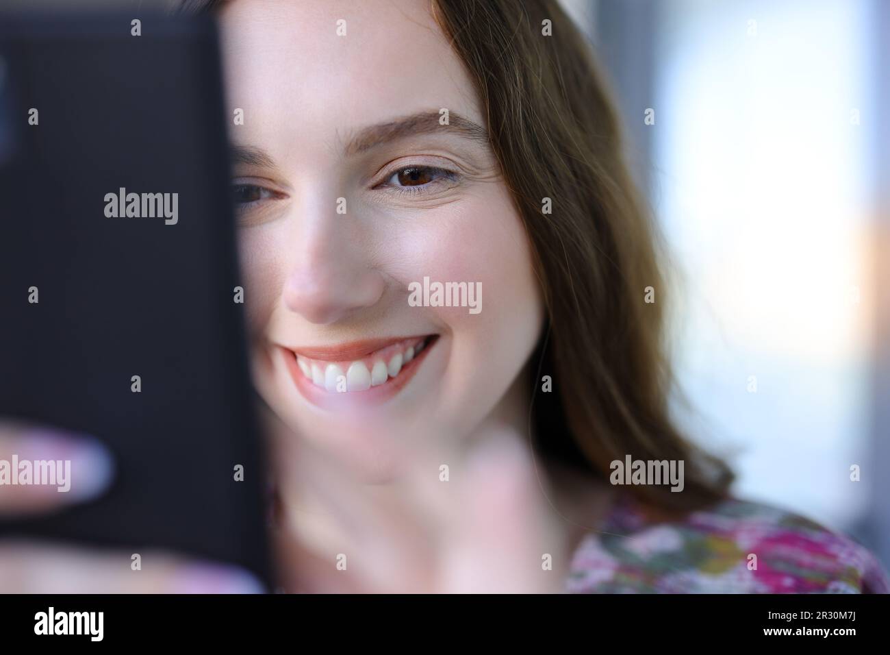 Close up of a happy woman using phone in the street Stock Photo