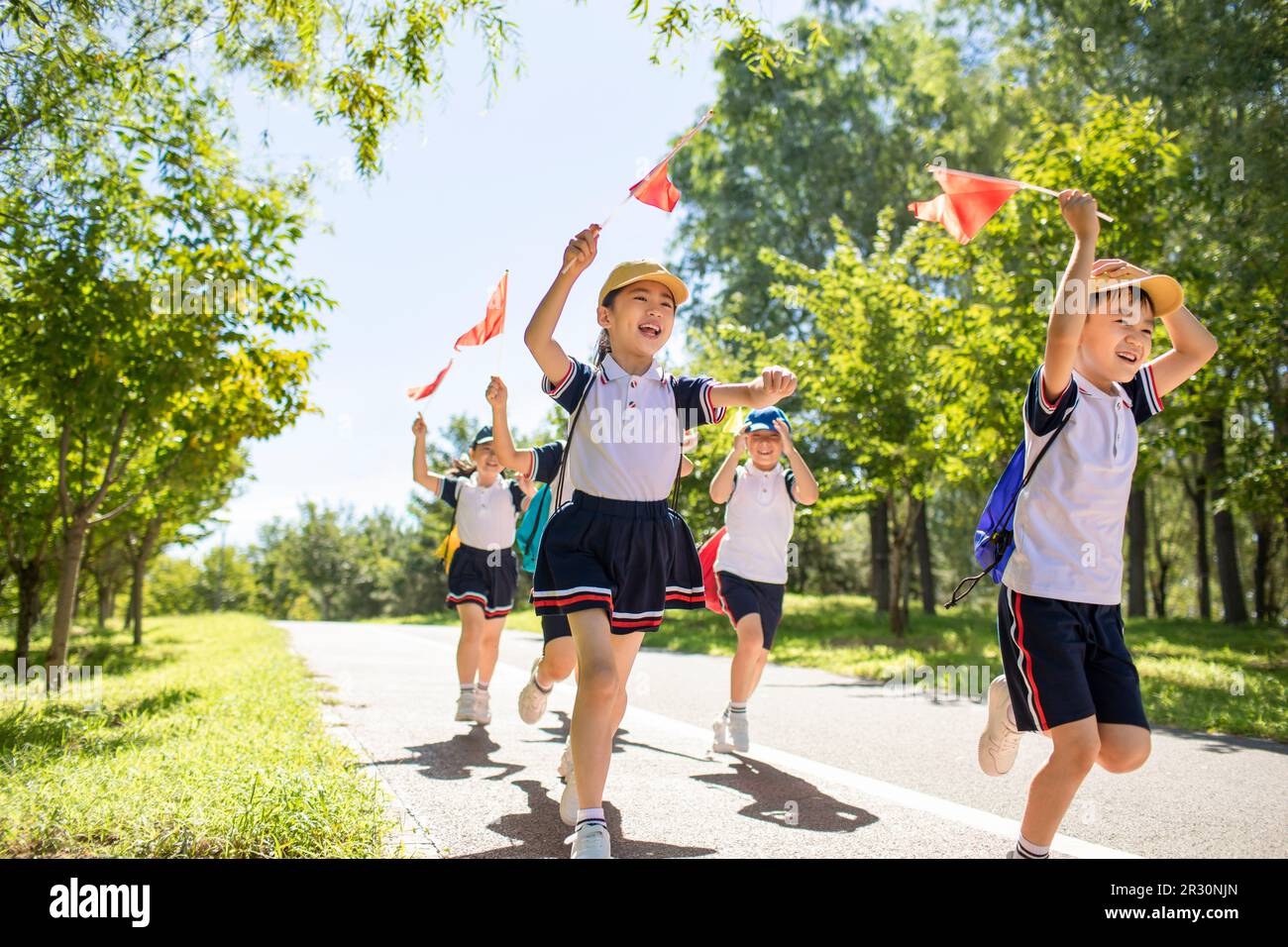 Cheerful Chinese school children relaxing in park Stock Photo