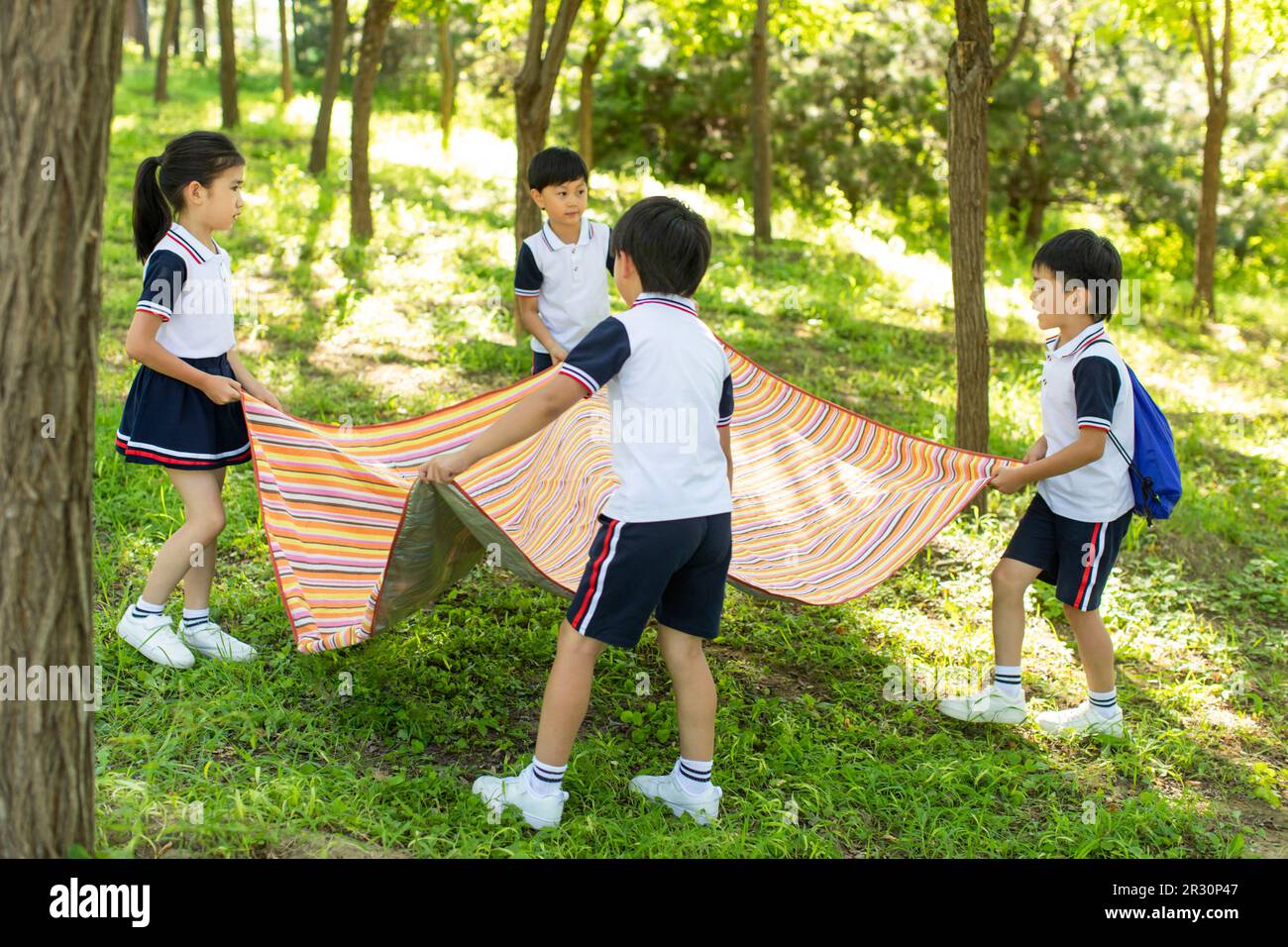 Cheerful Chinese school children picnicking outdoors Stock Photo