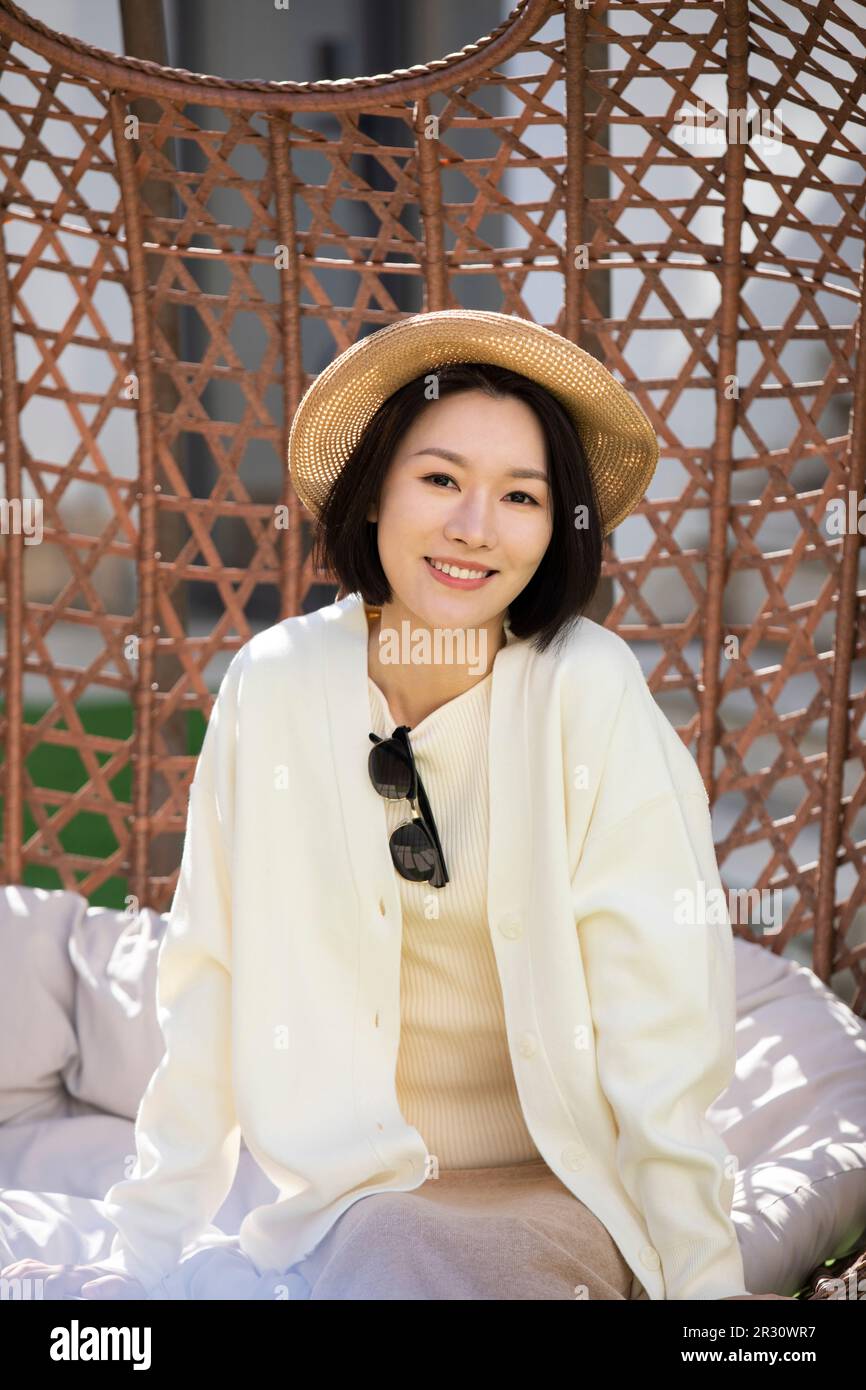 Happy young Chinese woman relaxing on hanging-chair Stock Photo