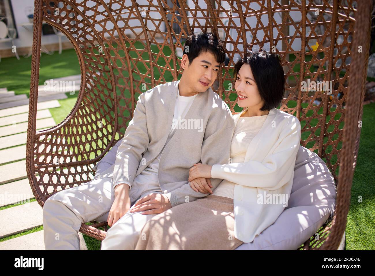Happy young Chinese couple relaxing on hanging-chair Stock Photo - Alamy