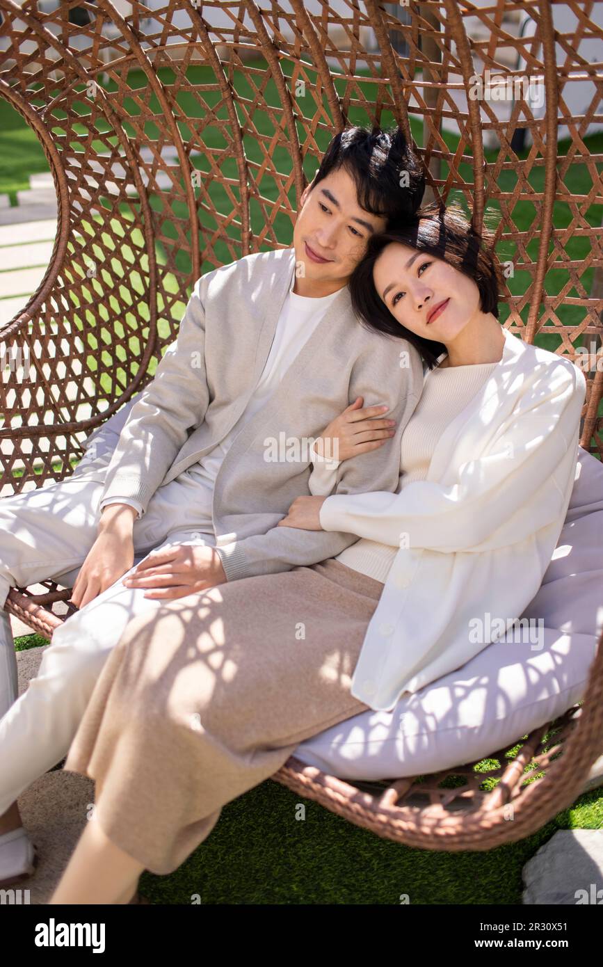 Happy young Chinese couple relaxing on hanging-chair Stock Photo - Alamy