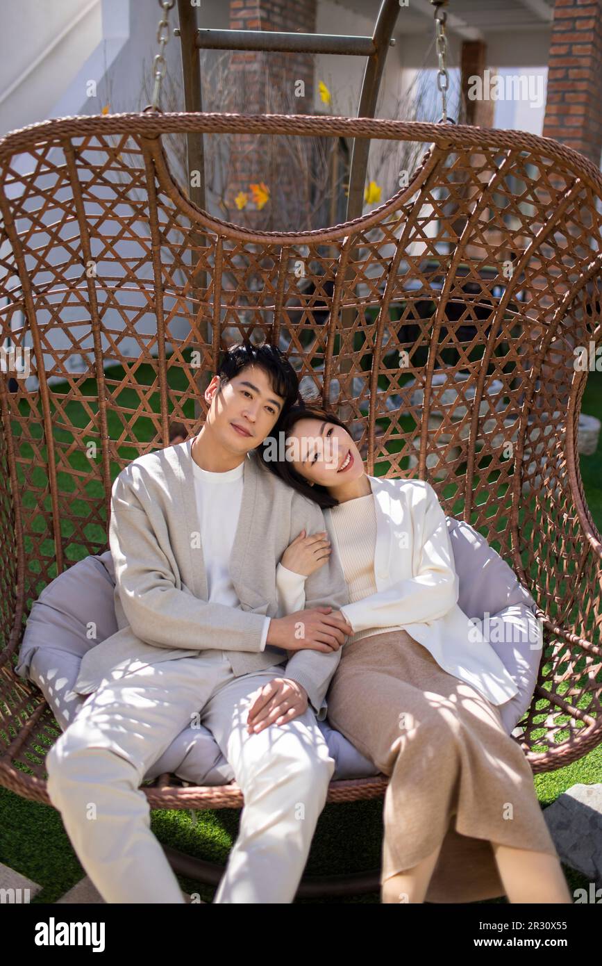 Happy young Chinese couple relaxing on hanging-chair Stock Photo - Alamy
