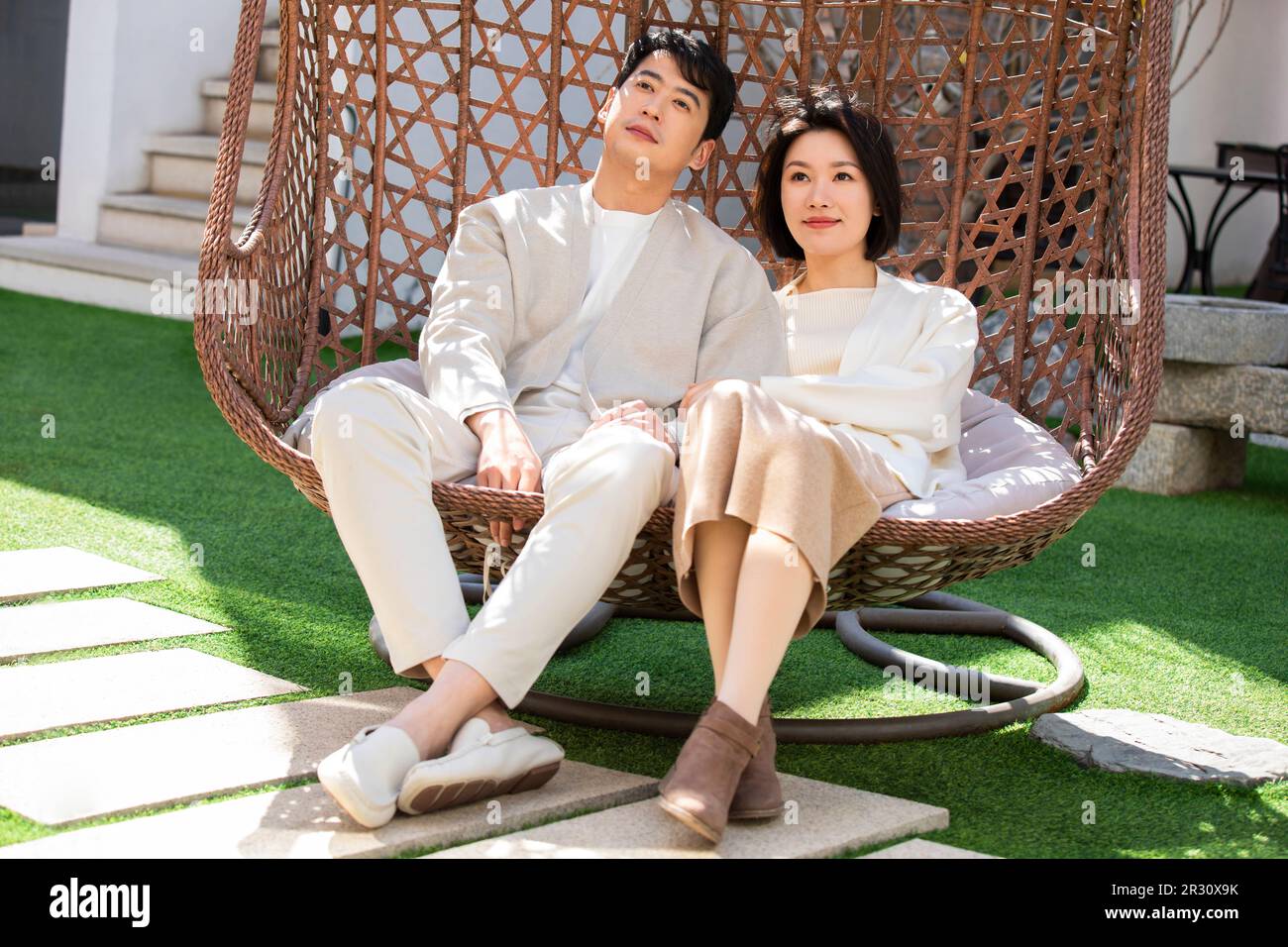 Happy young Chinese couple relaxing on hanging-chair Stock Photo - Alamy