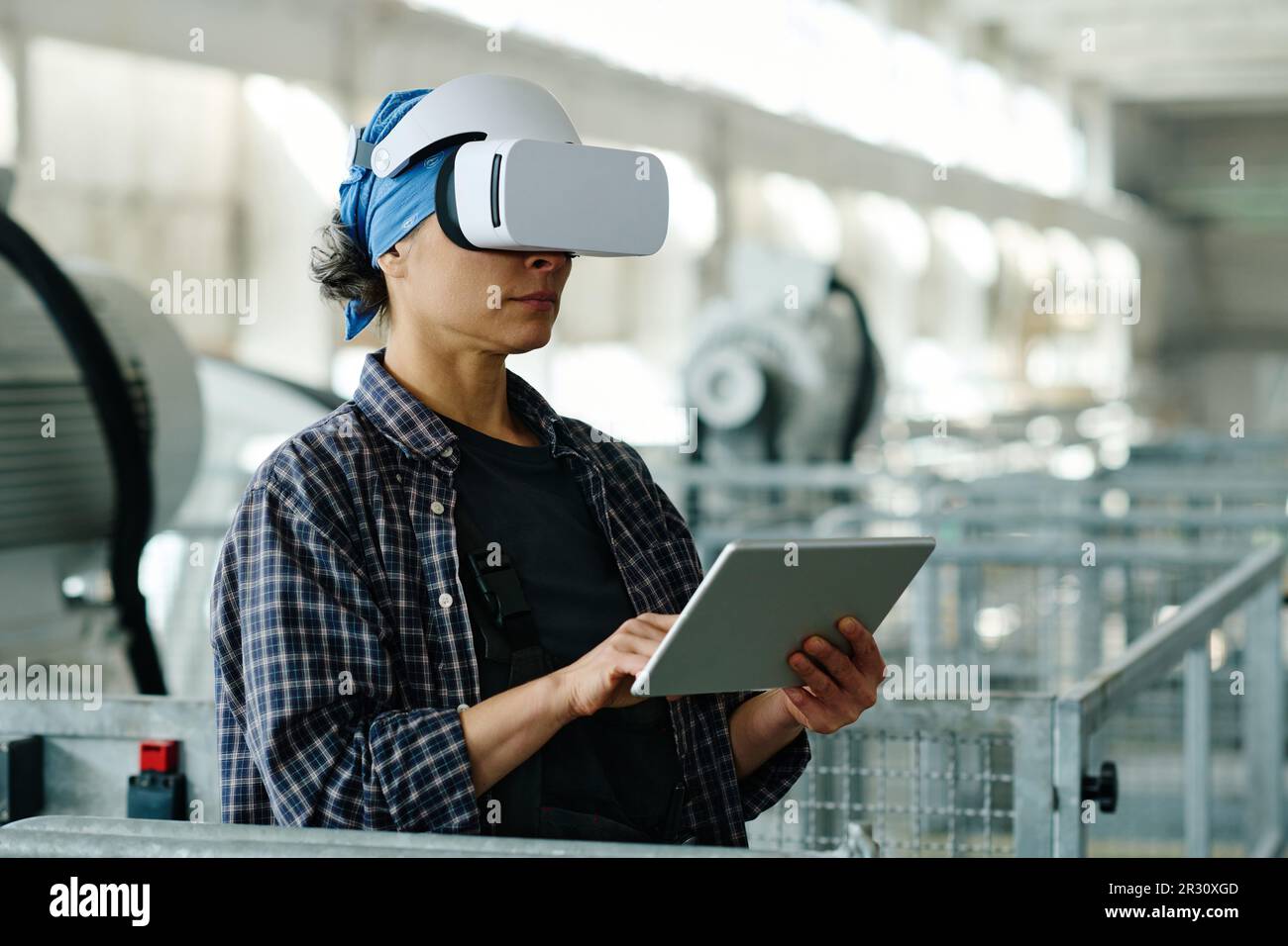 Female engineer connecting tablet pc with VR glasses and using them in