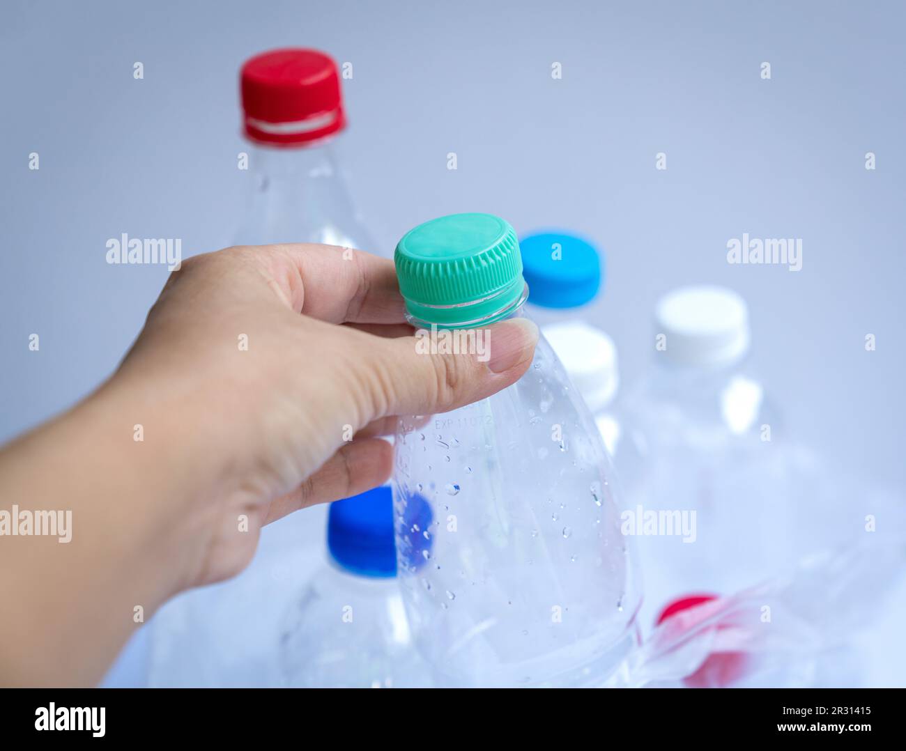 Hand putting a plastic bottle inside a plastic bag filled with bottles