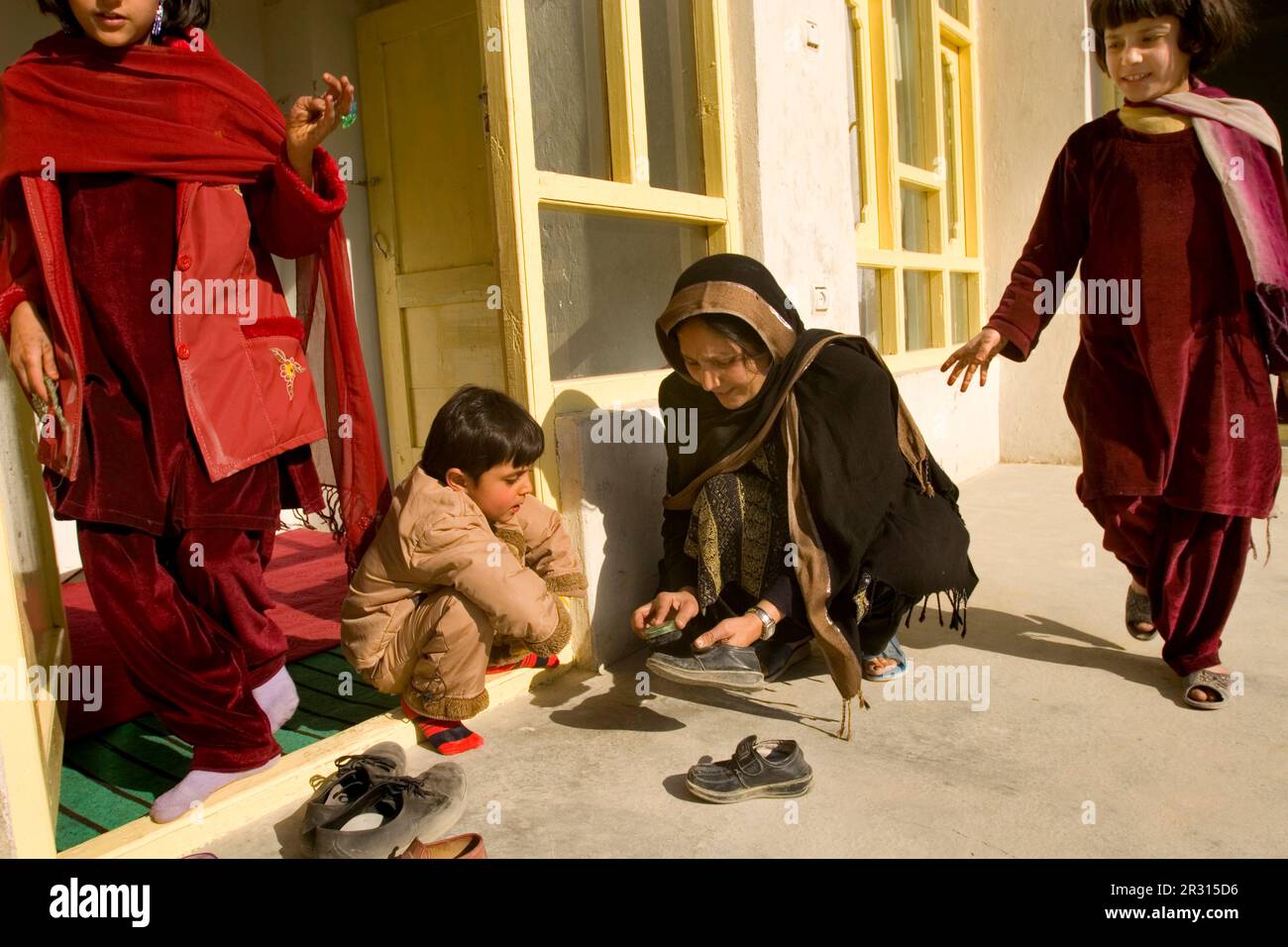 Woman helps her son clean his shoes in Kabul. Stock Photo