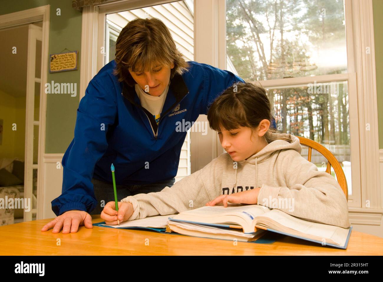 A mother helps her ten-year-old daughter with her homework. Stock Photo