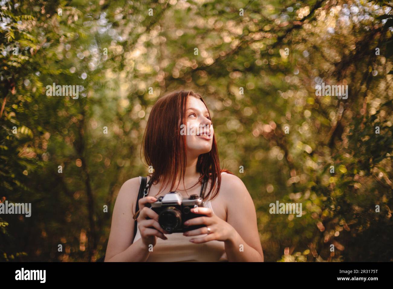 Young woman holding camera in forest Stock Photo