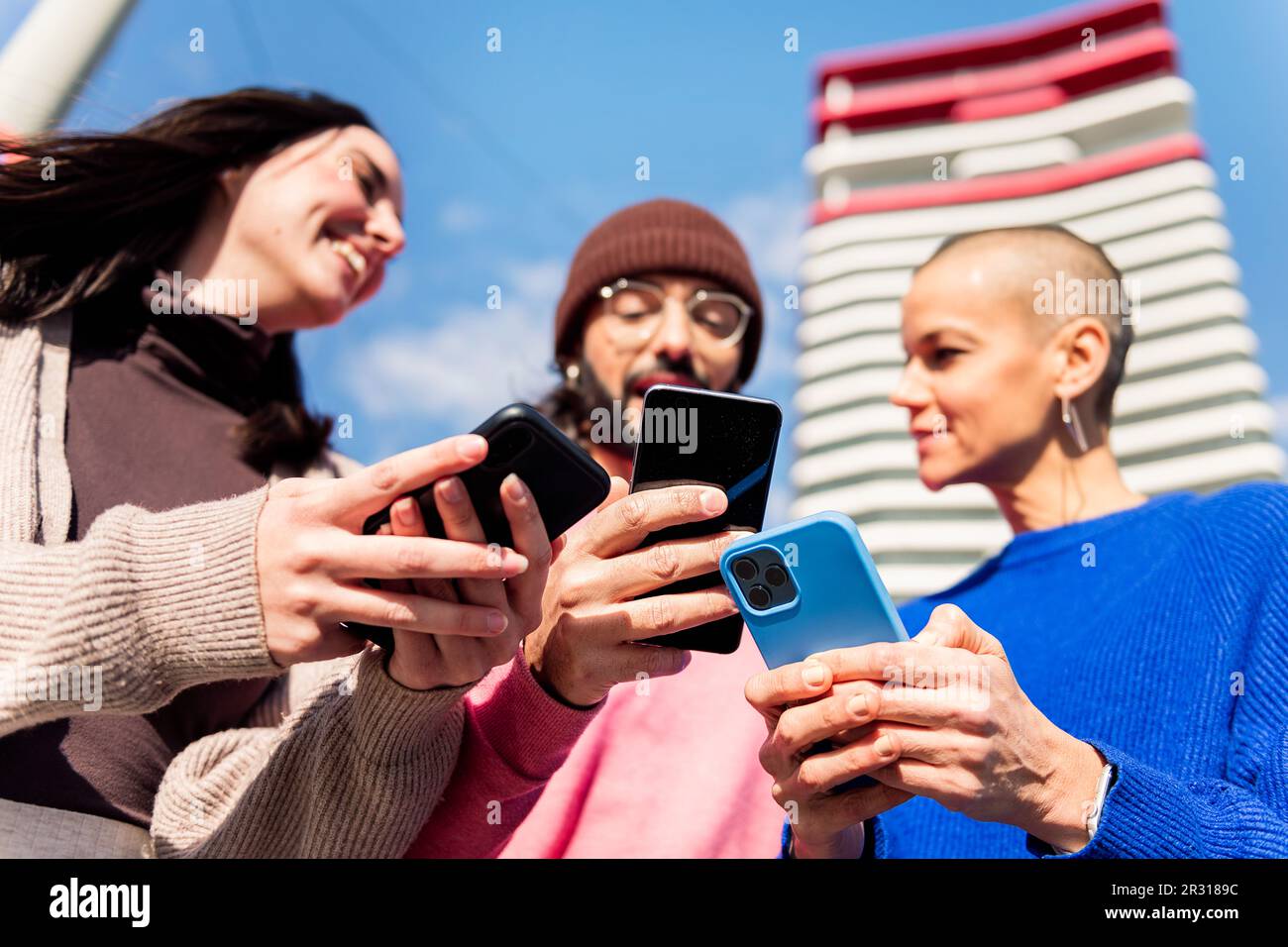 three young friends having fun using mobile phones Stock Photo