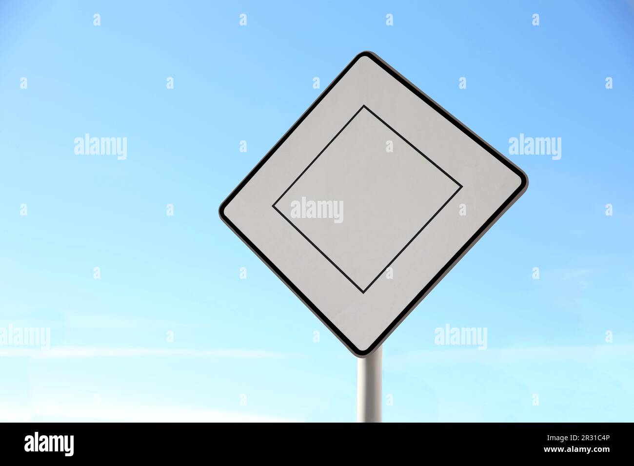 Priority road sign against blue sky on city street Stock Photo