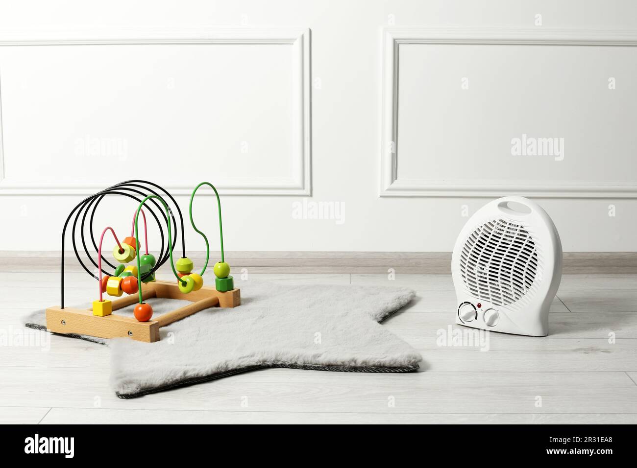 Modern electric fan heater and colorful toy on rug indoors Stock Photo
