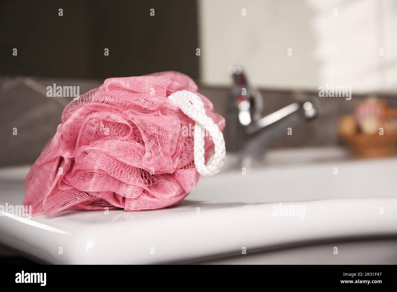 Pink shower puff on washbasin in bathroom, closeup. Space for text ...