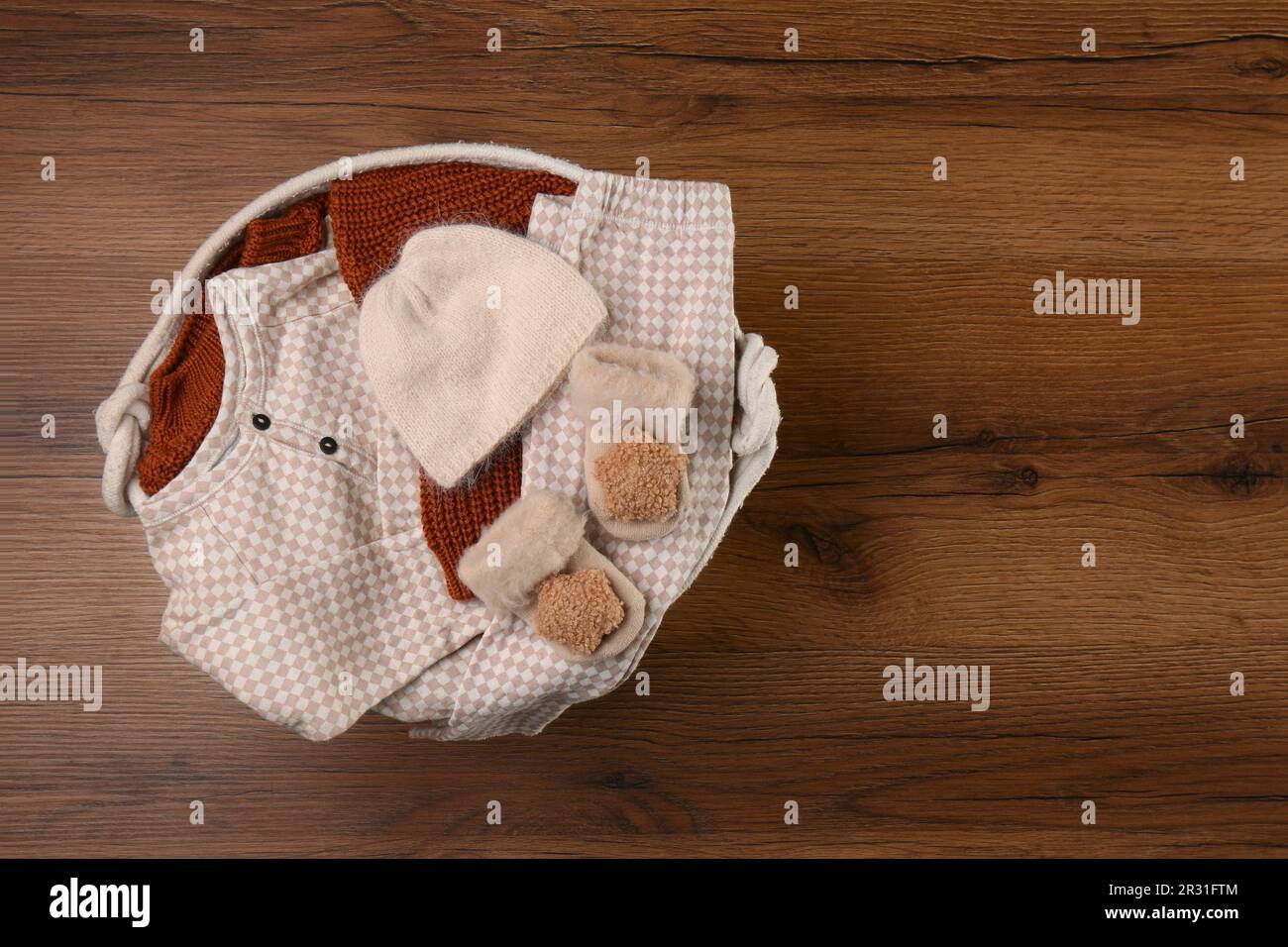 Laundry basket with baby clothes on wooden table, top view. Space for ...