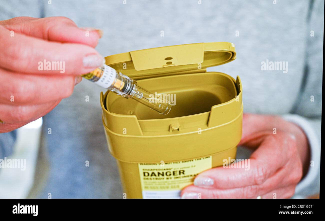 Woman disposing of a used needle in a Sharpsguard disposal waste unit