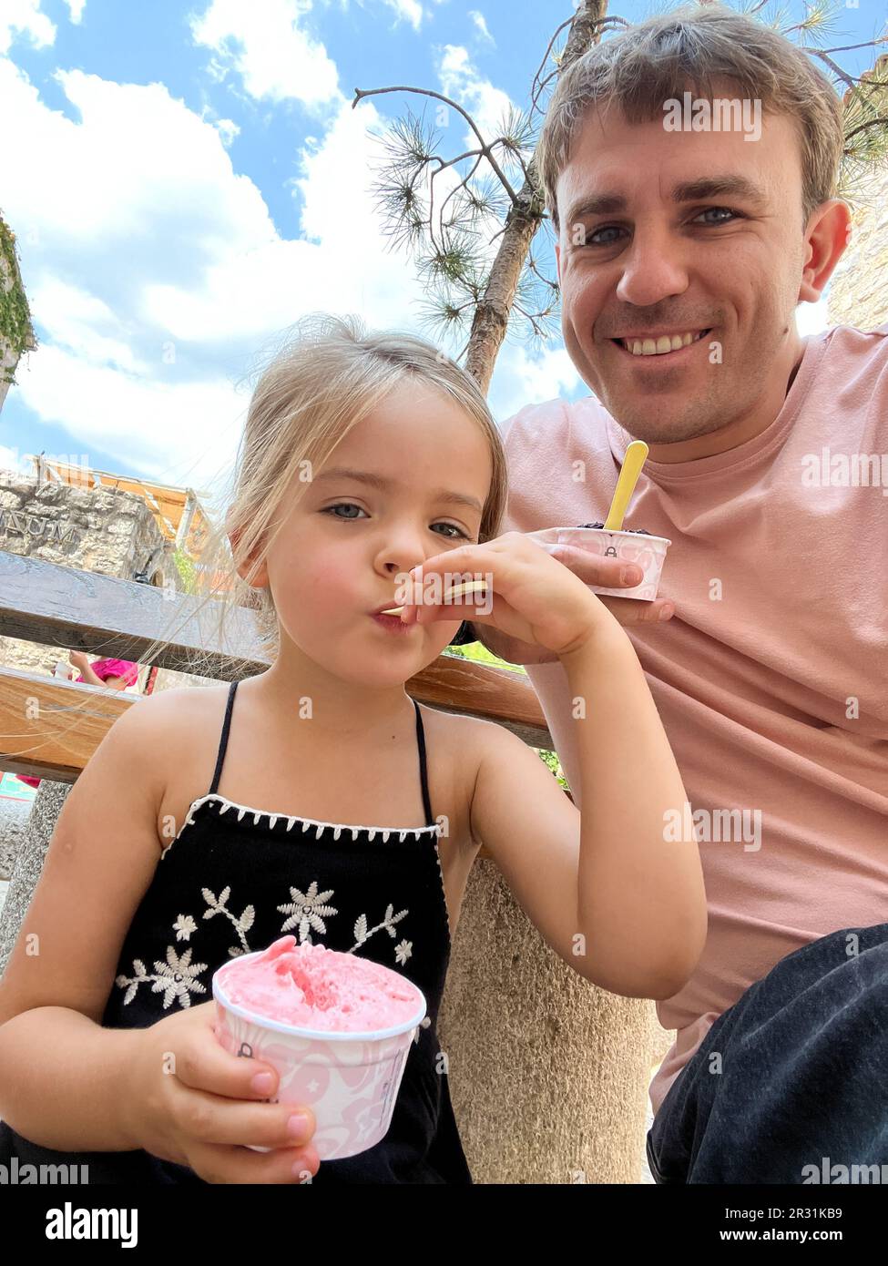 Dad and little girl eat ice cream with scoops from cups Stock Photo Alamy