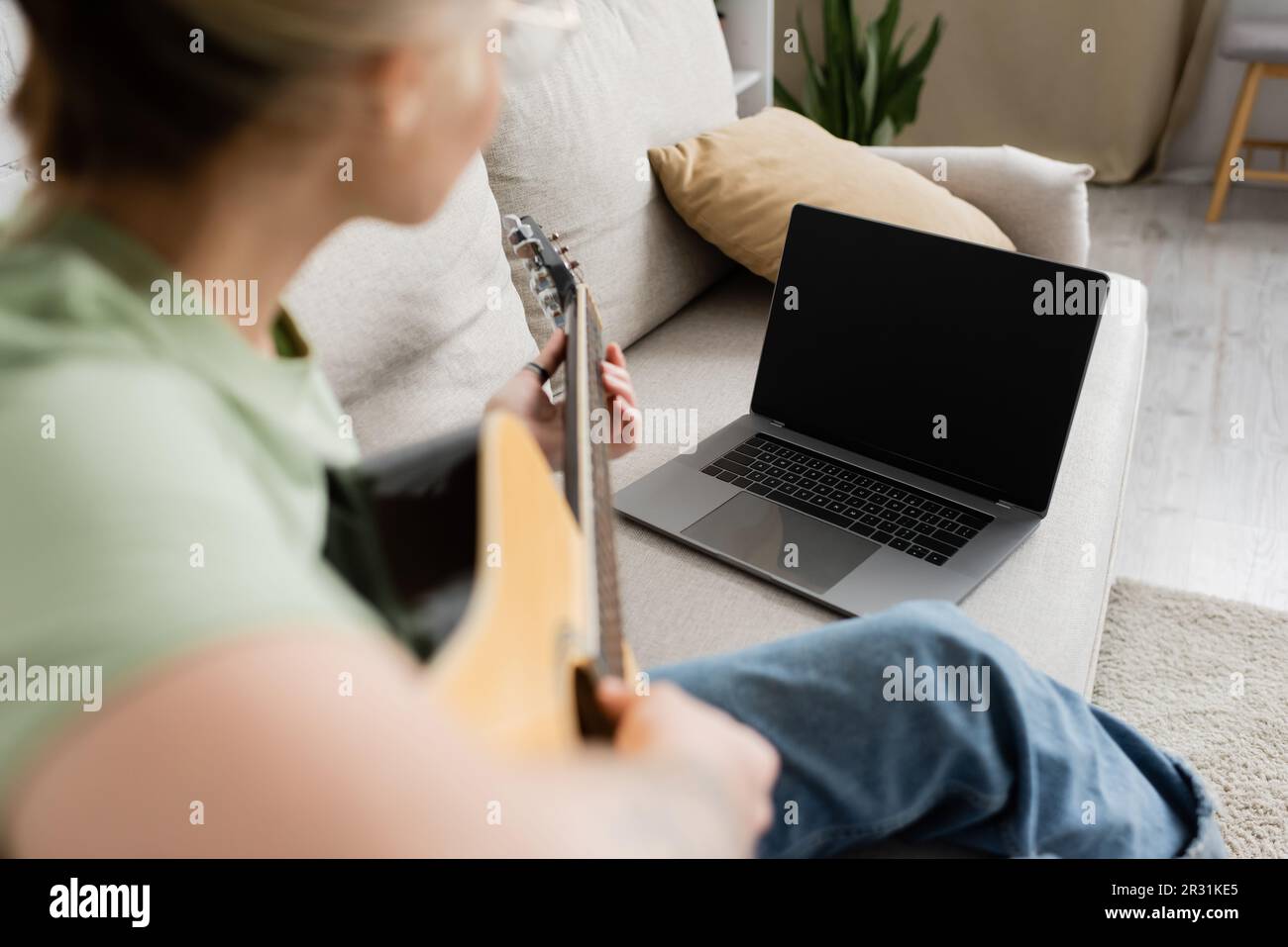 blurred young woman holding acoustic guitar and learning how to play
