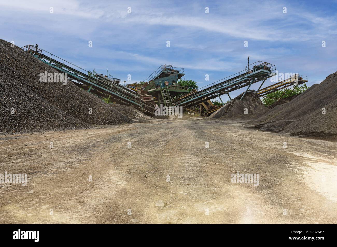 https://c8.alamy.com/comp/2R326P7/crushing-machinery-cone-type-rock-crusher-conveying-crushed-granite-gravel-stone-in-a-quarry-open-pit-mining-minning-industry-gravel-quarry-convey-2R326P7.jpg