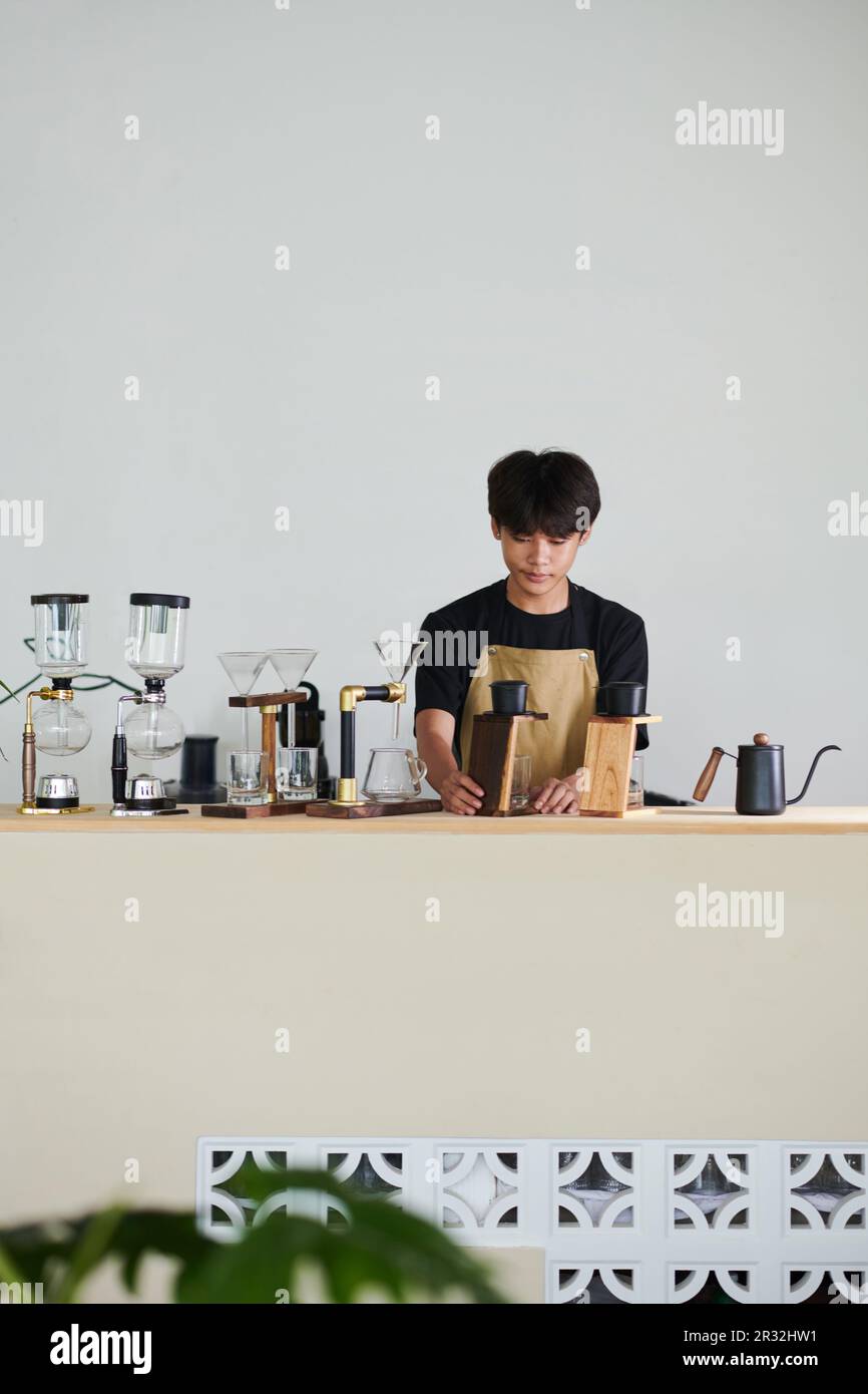 Pensive young man working in coffeeshop, using phin drip filter when making coffee Stock Photo