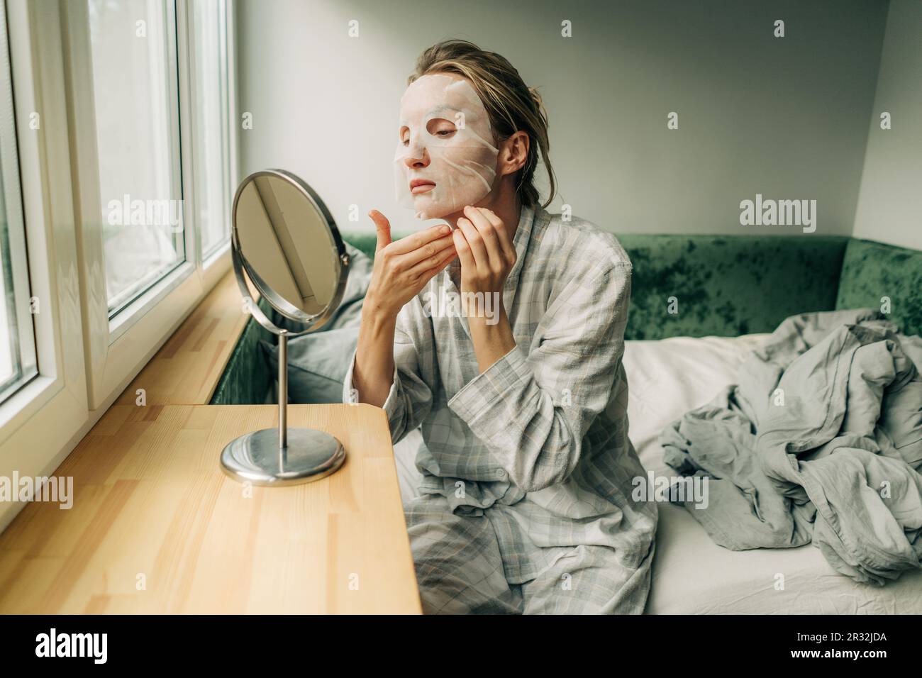 Woman using a cosmetic tissue face mask for selfcare. Stock Photo
