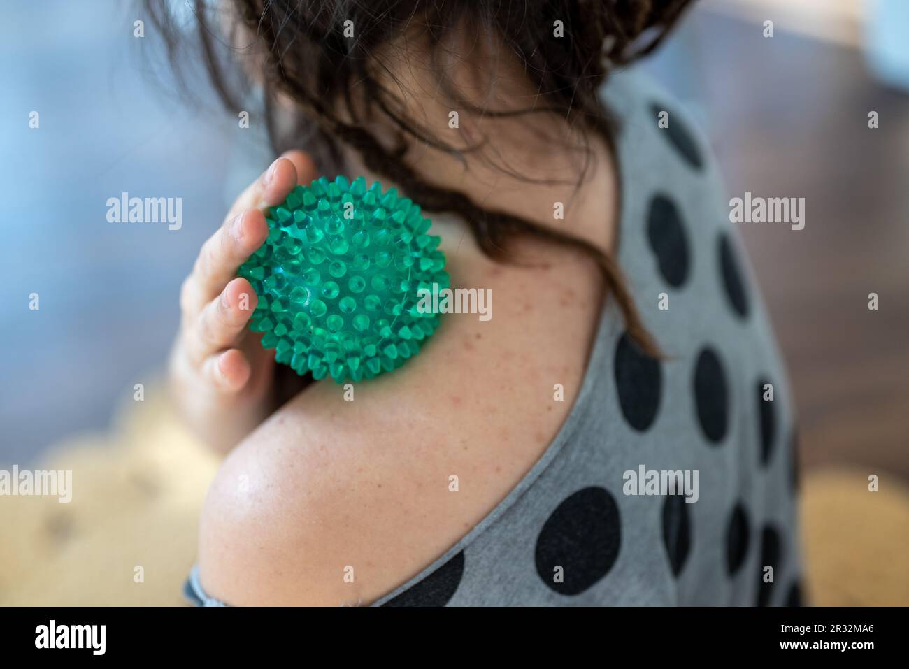 young woman releasing her trapezius musce with a spiky massage ball ...