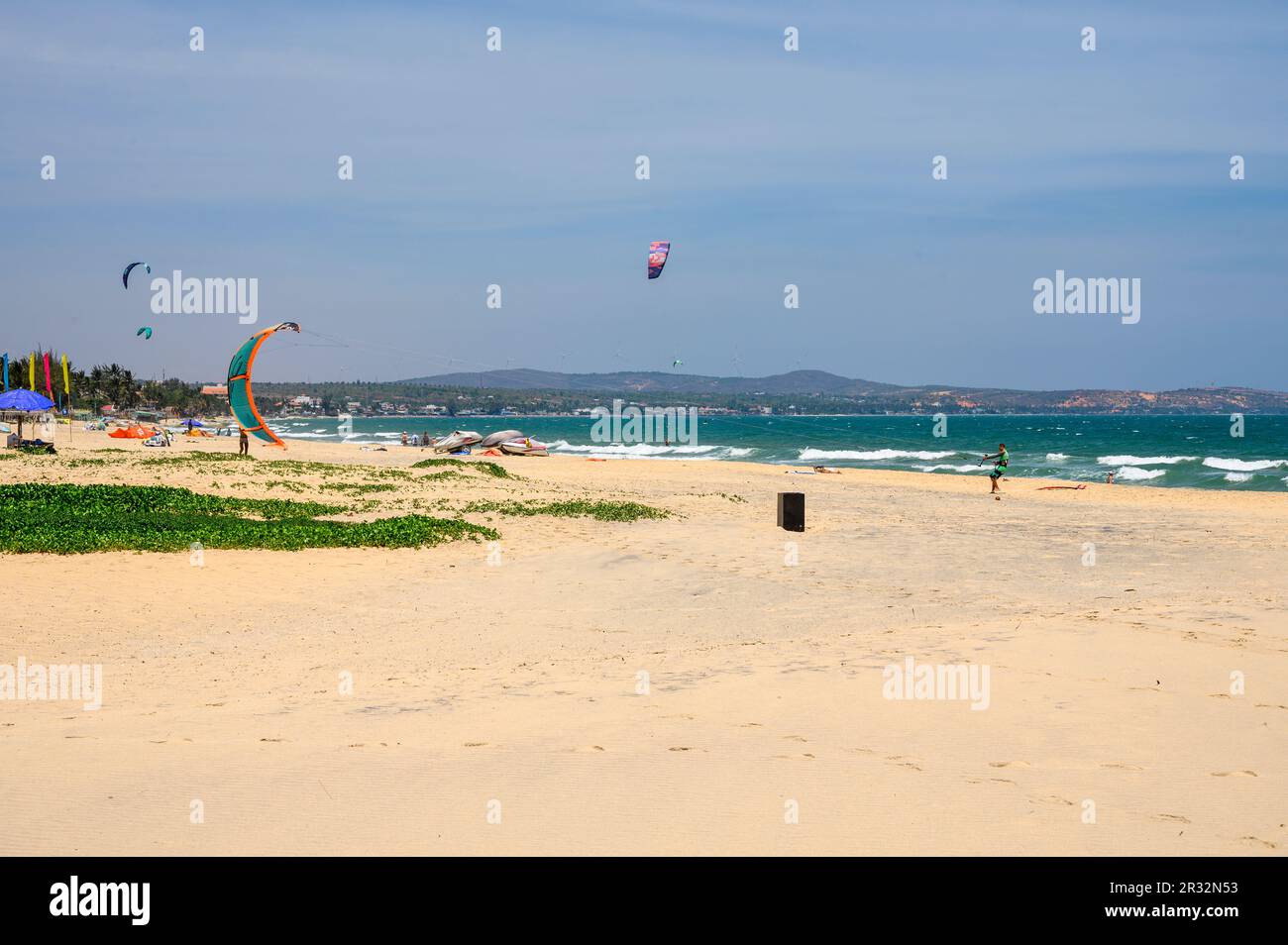Kitesurfers in action on and off the fine, sandy beach in Mui Ne, Vietnam. Stock Photo