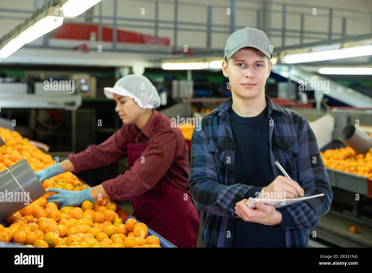 Young supervisor inspecting workflow of citrus sorting workshop Stock ...