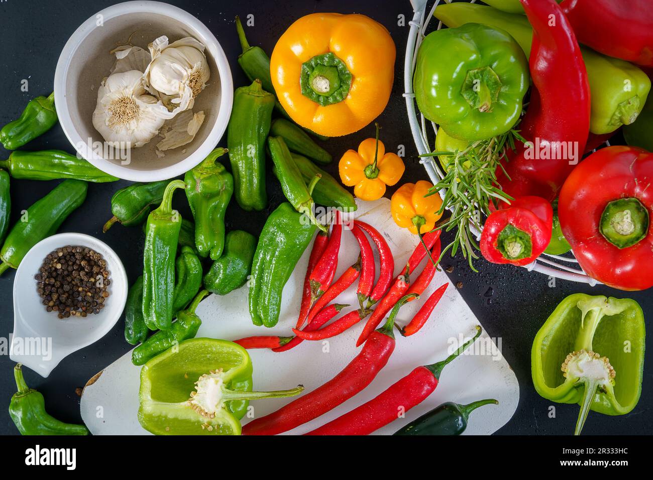 a colorful assortment of peppers, hot peppers and chili, decorated with various assesoires on a wooden table. Stock Photo