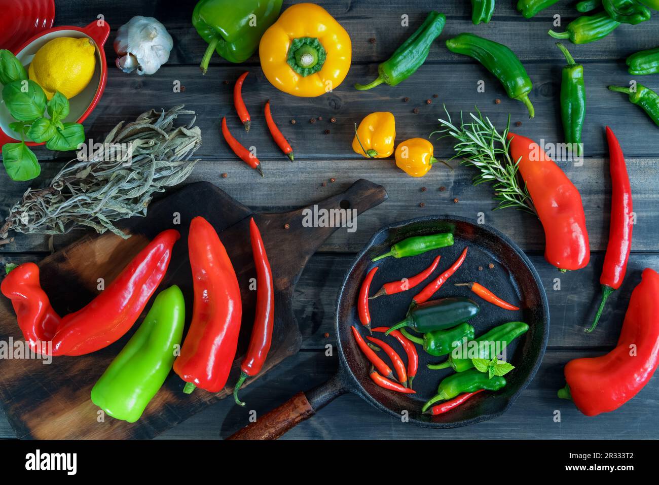 a colorful assortment of peppers, hot peppers and chili, decorated with various assesoires on a wooden table. Stock Photo