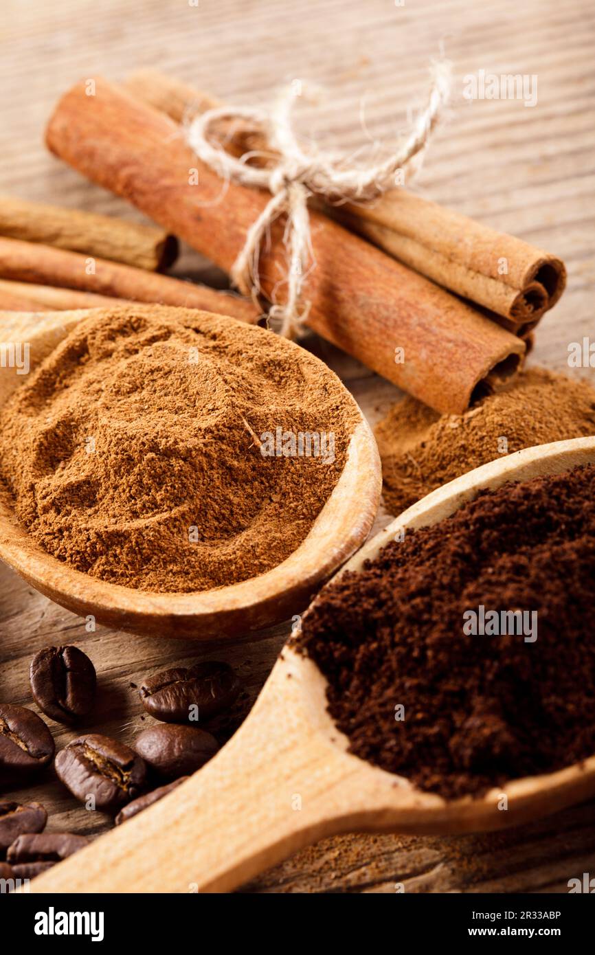 White cup of coffee and cinnamon tubes, spoon with ground coffee