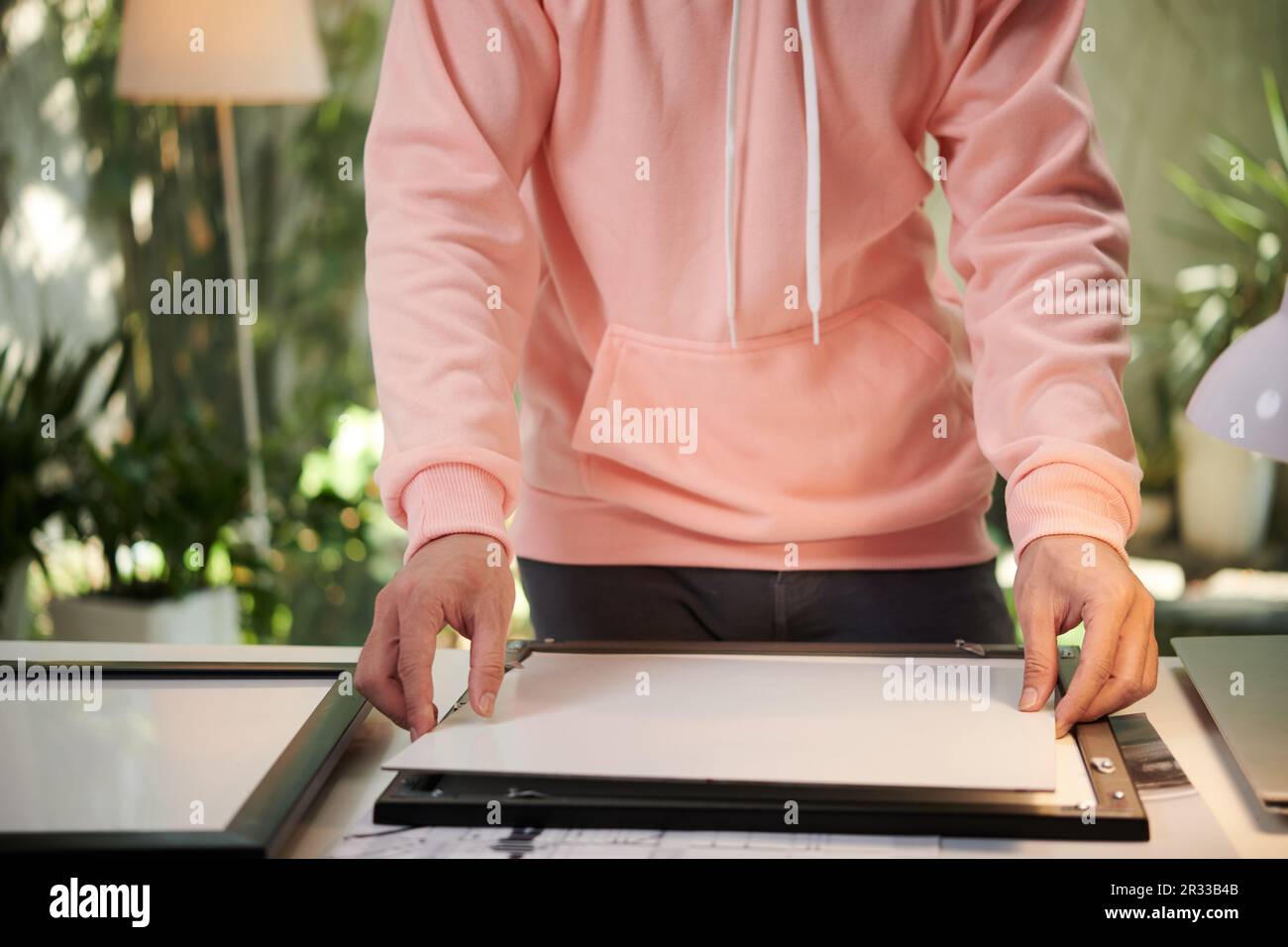 Hands of photographer putting printer photos into frames for exhibition