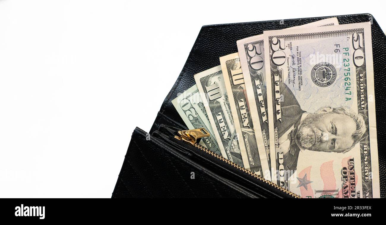 USD cash money in a big pile. Paper money in a black, leather wallet close up. Cash of paper currency background, isolated on white background. Stock Photo