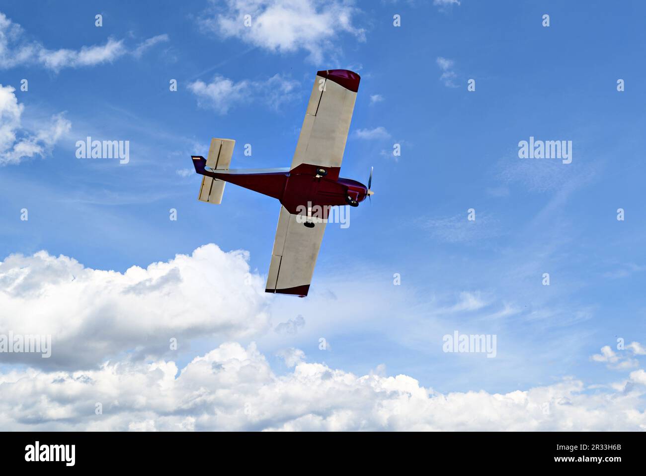 Single engine ultralight plane flying in the blue sky with white clouds Stock Photo