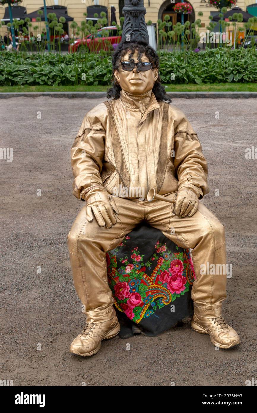 A silent motionless theatrical street performer in a gold painted costume in Esplanadi park in Helsinki, Finland. Stock Photo
