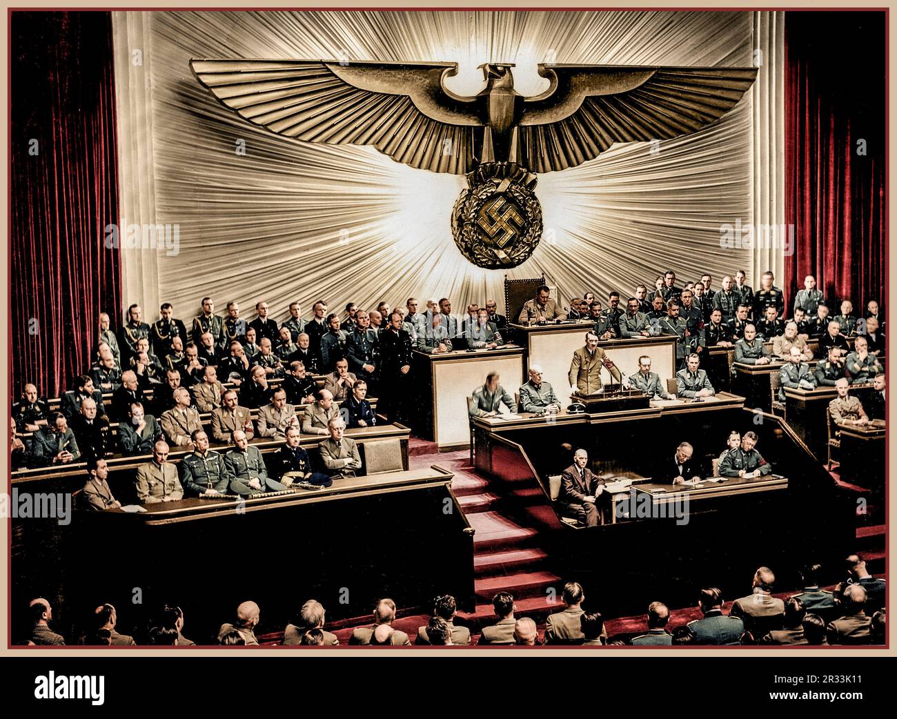 Adolf Hitler delivering a speech at Kroll Opera House (colour image) before the men of the Reichstag on the subject of Roosevelt and the war in the Pacific, declaring war on the United States. Next to Hitler in the government benches (from right to left) are Joachim von Ribbentrop, Erich Raeder, Walther von Brauchitsch, Wilhelm Keitel, Wilhelm Frick and Joseph Goebbels. 28/4/1939 Stock Photo